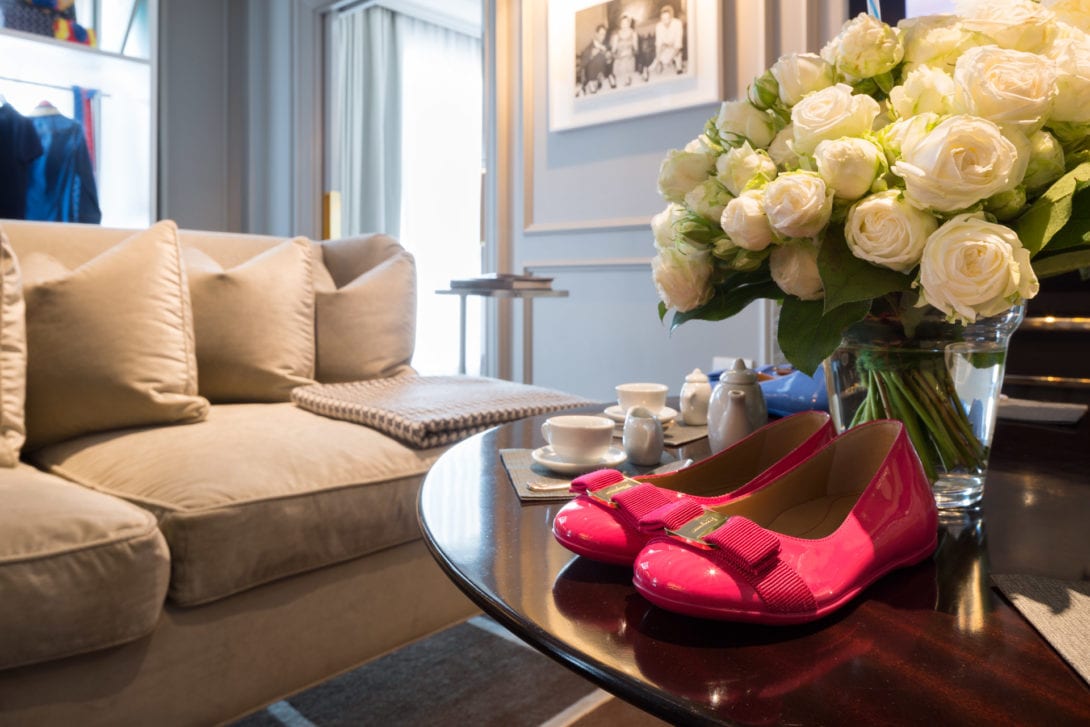 Eleganti calzature rosa per bambina esposte sul tavolino di design della suite