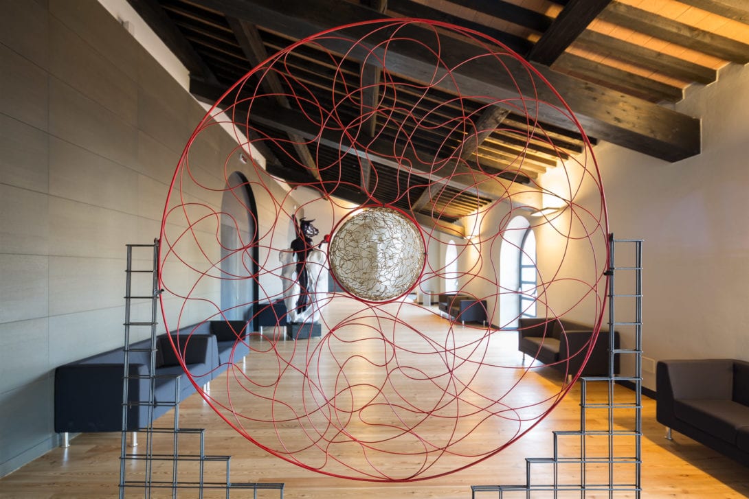 Installazione artistica in filo metallico sotto le storiche capriate in legno dell'ex fonderia