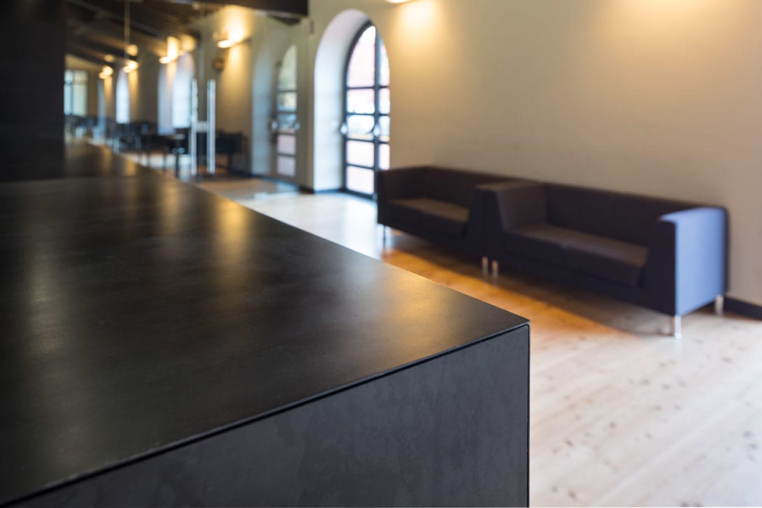 Dettaglio prospettico del bancone scuro nel foyer, fotografo interni architettura industriale Toscana