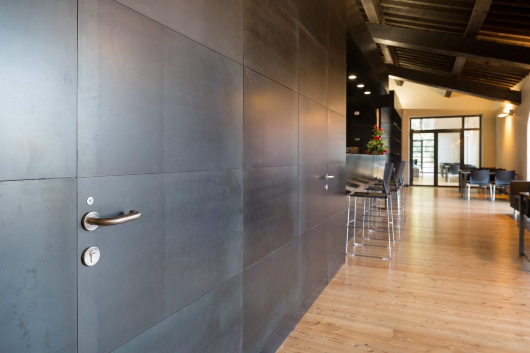 Corridoio con pannellature metalliche nere che richiamano il passato industriale dell'edificio