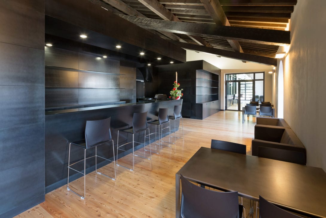 Area lounge e bar con sgabelli di design integrata perfettamente sotto la copertura lignea