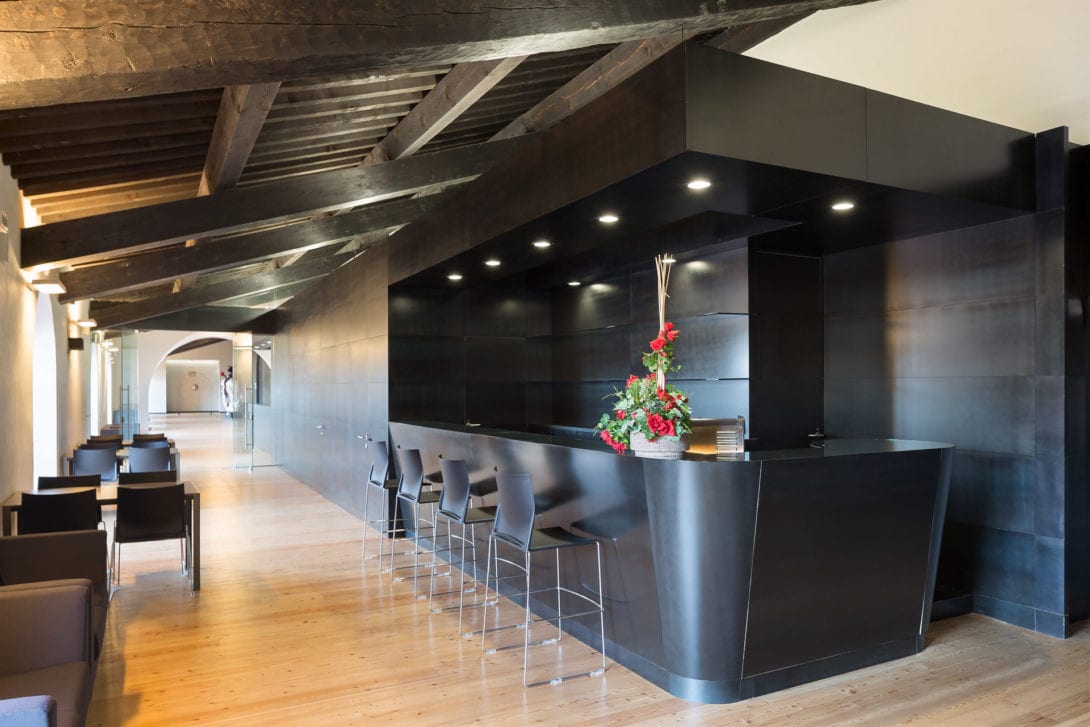 Prospettiva dell'elegante area bar del teatro con elementi in stile industriale e luci soffuse