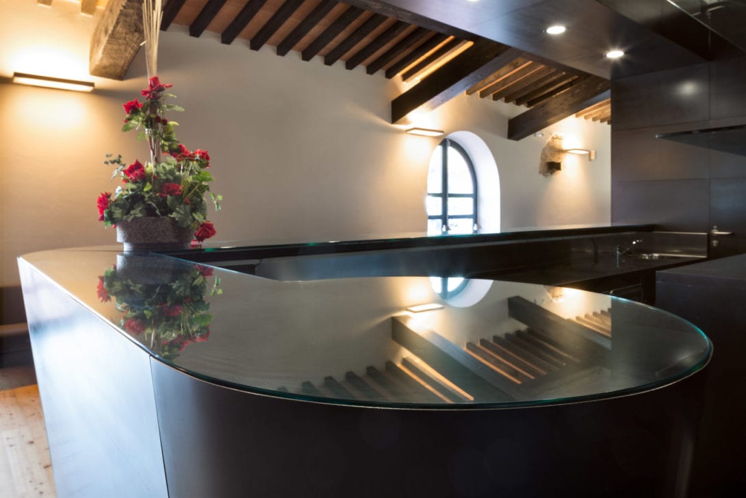 Riflessi delle storiche travi in legno sulla superficie lucida del moderno bancone